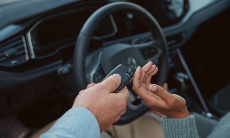 Ein Volkswagen Service Mitarbeiter übergibt einen Autoschlüssel an eine Kundin. Zu sehen sind nur die Hände.