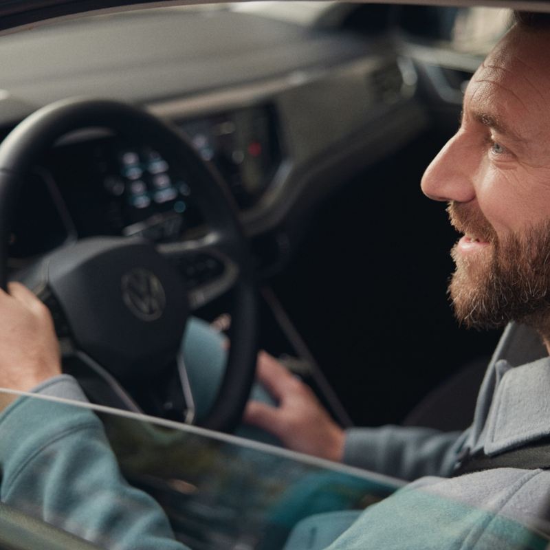 Ein zufriedener Mann sitzt im Cockpit eines Volkswagen Taigo.