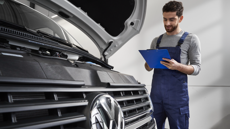 Una empleado del Servicio Oficial con una tablet al lado de un vehículo VW.