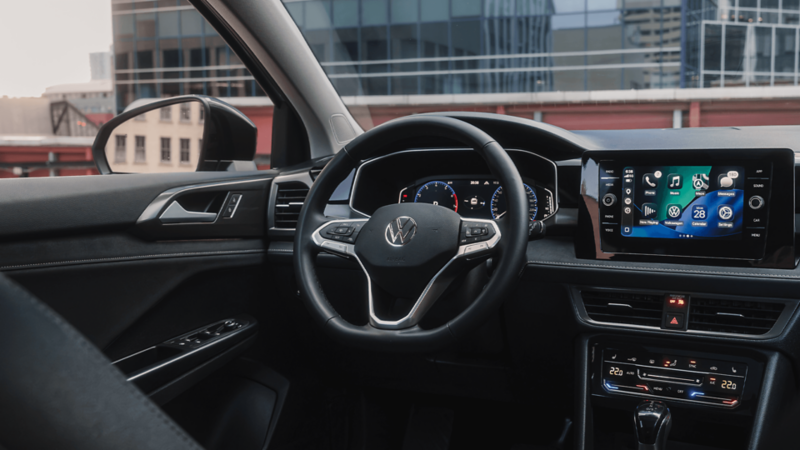 Vue intérieure depuis le poste de conduite montrant le volant, le combiné d’instruments numérique et l’écran tactile central du Volkswagen Taos.