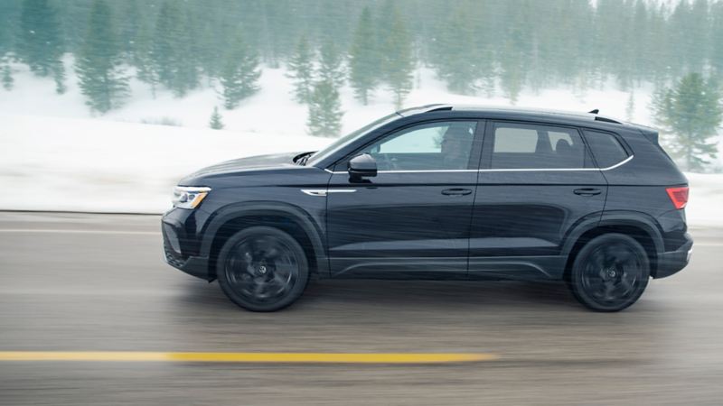 The black 2024 Volkswagen Atlas driving on the highway during winter