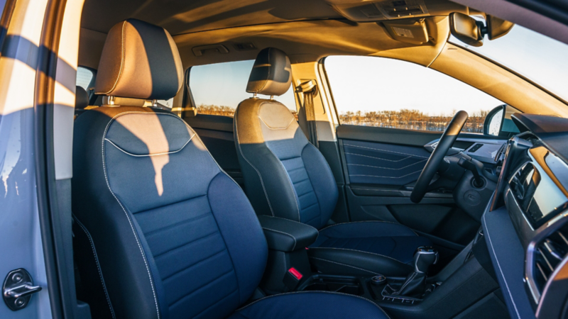 Interior view of the Volkswagen Taos showing the front seats with two-tone blue and tan leather upholstery, with golden hour light coming through the windows.