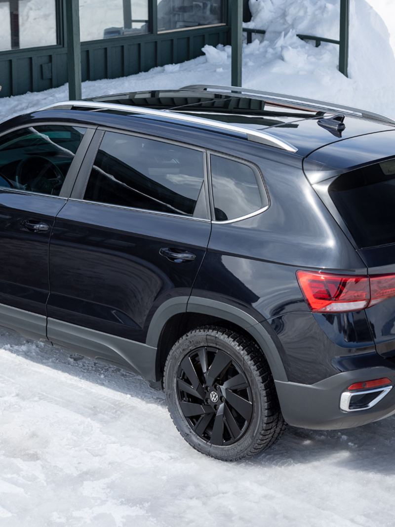 The black 2024 Volkswagen Taos parked near a porch during the winter