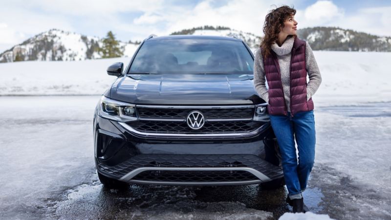 A woman standing in front of the parked 2024 Volkswagen Taos