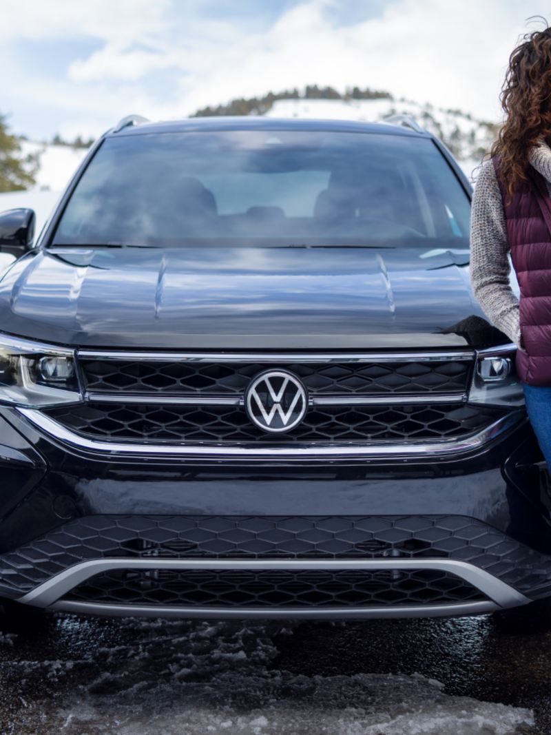 A woman standing in front of the parked 2024 Volkswagen Taos