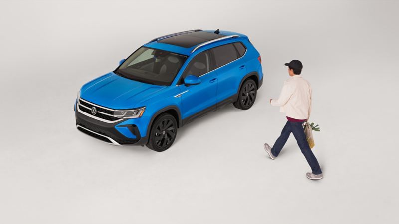 Un homme s’approche d’un Taos 2024 de VW bleu stationné