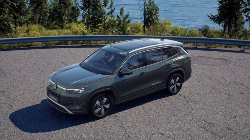 A dark green Tayron Match parked by a body of water near a forest