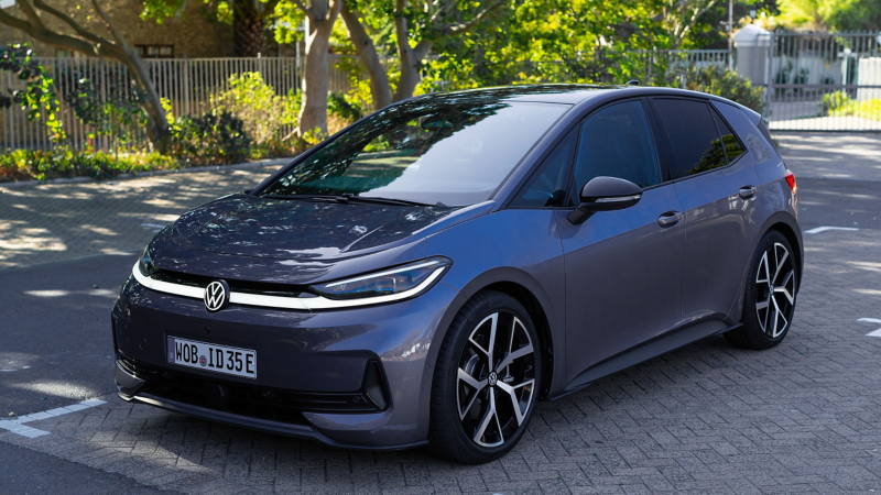 ID.3 Neo in grau auf einem Parkplatz vor einem umzäunten Park.