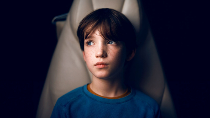 A young boy is sitting in a Volkswagen and is looking to the left