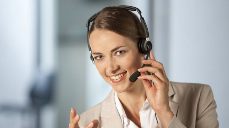 Une femme souriante porte un casque de téléopérateur.