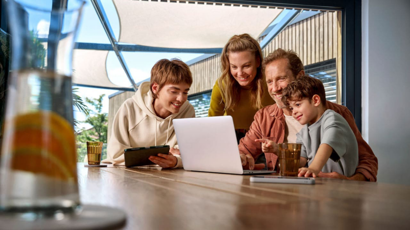 Gezin zit samen achter de laptop aan de keukentafel
