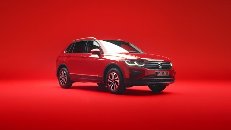 Czerwony VW Tiguan widziany z przodu i z boku na czerwonym tle.