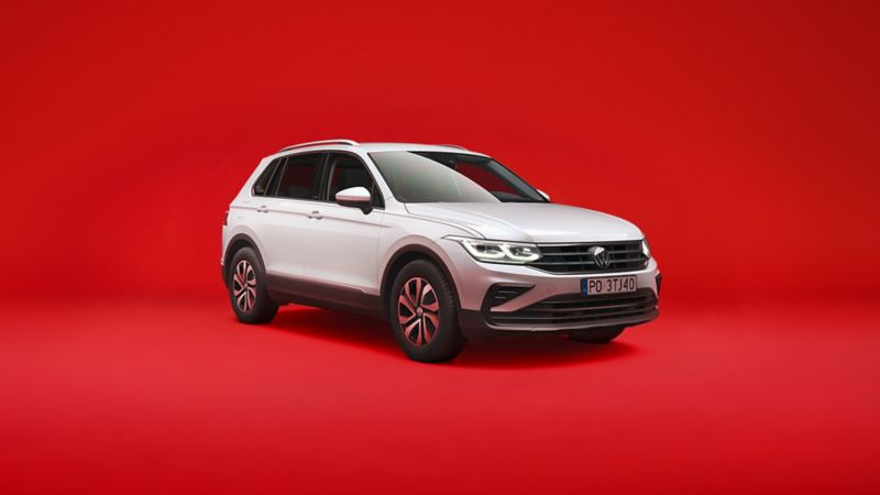 Biały VW Tiguan eHybrid Plug-in widziany z przodu i z boku na czerwonym tle.