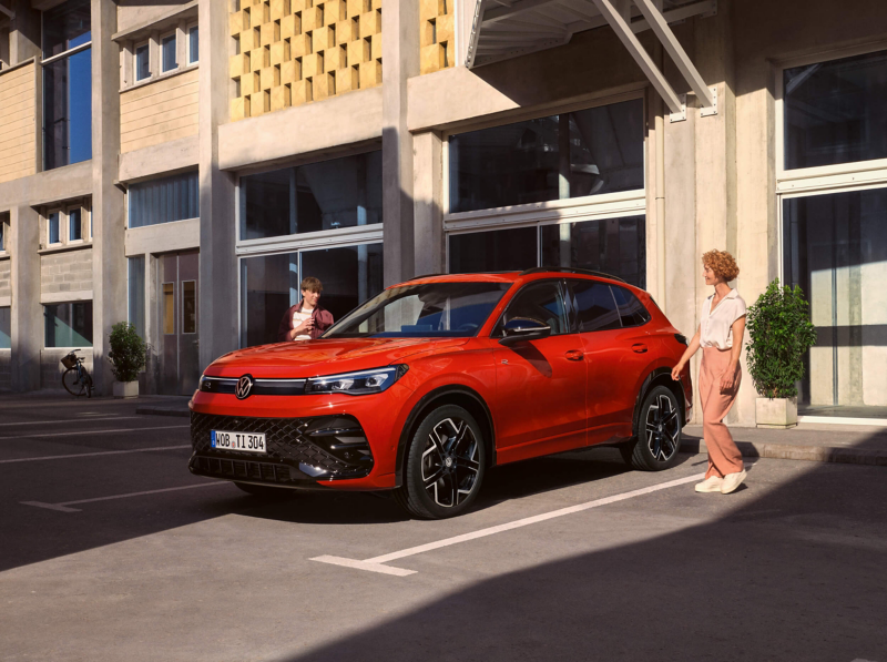 a red Volkswagen Tiguan with two people walking towards it