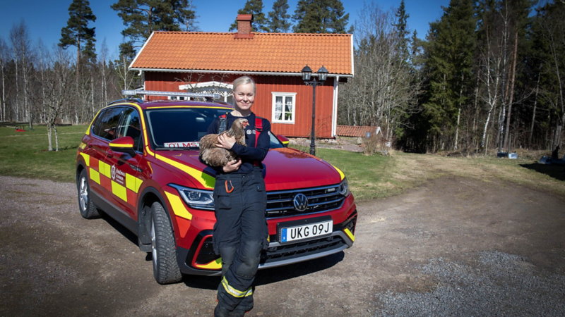 Deltidsbrandmannen Elna Dahlstrand står framför sin Tiguan med en höna i famnen