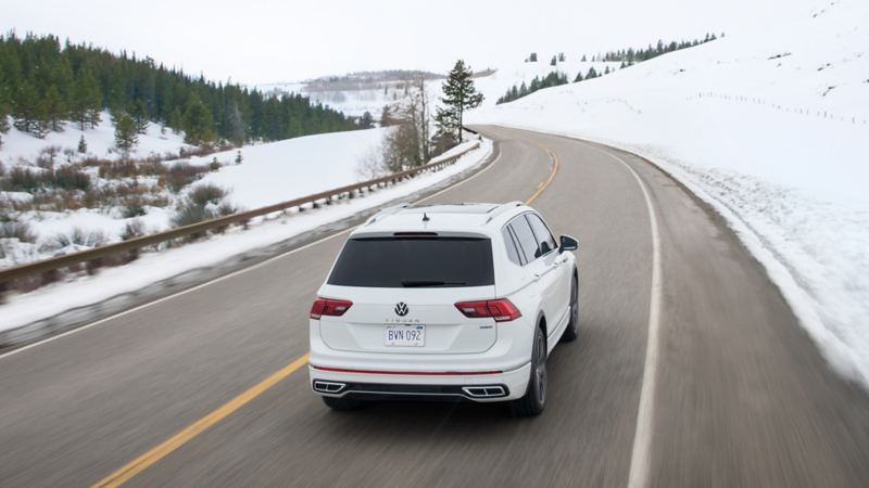The white 2024 Volkswagen Tiguan driving on the road during winter