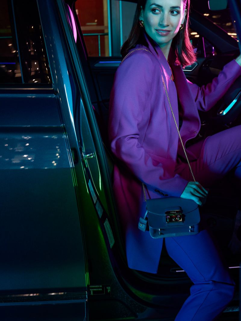 Woman sitting in drivers seat of Volkswagen Tiguan with door open.