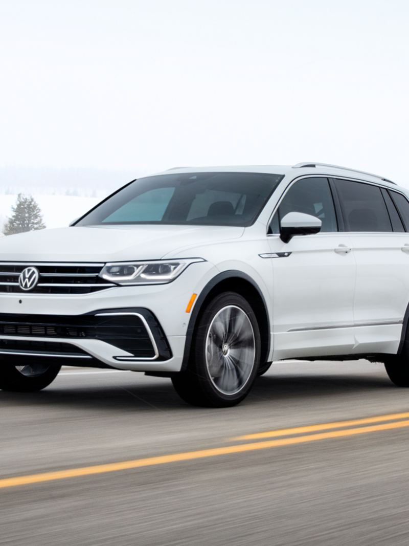 The white 2024 Volkswagen Tiguan driving on the highway during winter