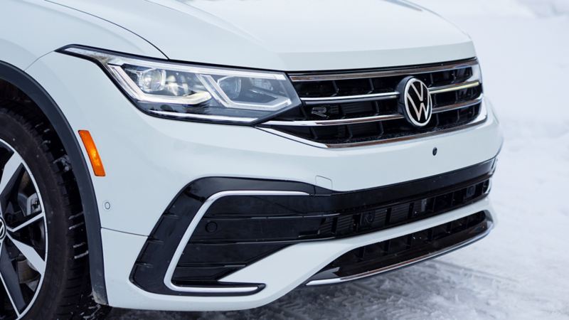 A close up photo of the white 2024 Volkswagen Tiguan’s grille and headlights