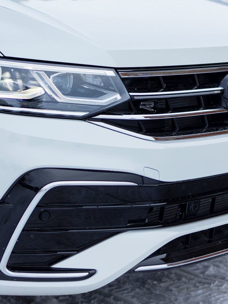 A close up photo of the white 2024 Volkswagen Tiguan’s grille and headlights