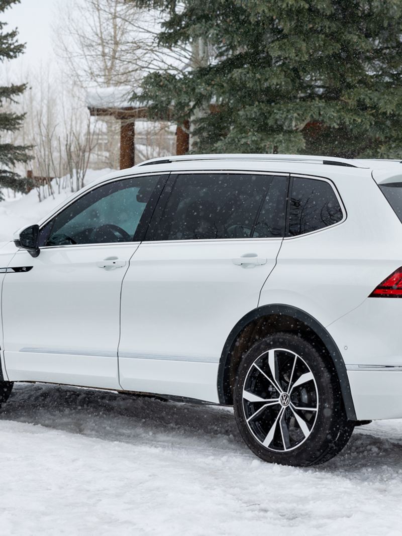 The white 2024 Volkswagen Tiguan parked on the snow near a wooden house
