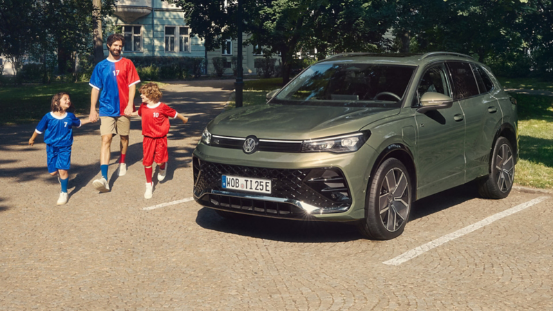 parents and child in the foreground with the new Tiguan in the background. 