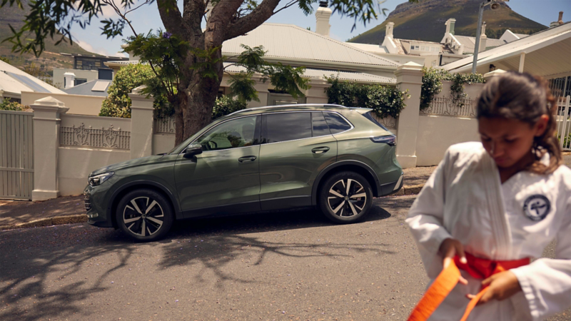 Un VW Tiguan est garé en arrière-plan, avec une jeune judokate au premier plan.