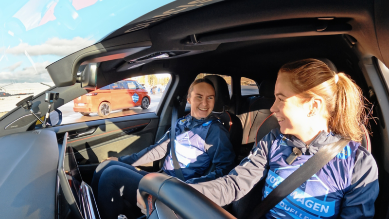 Två kvinnliga skidåkare sitter i en VW ID.7 Tourer och skrattar