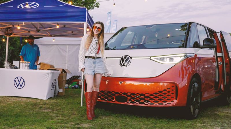 A young women posing next to the Volkswagen ID. Buzz
