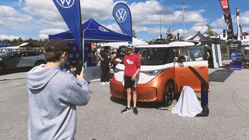 A teenager taking a photo of his friend and the Volkswagen ID. Buzz