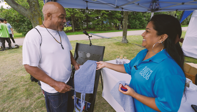 A Volkswagen rep handing a man some VW swag