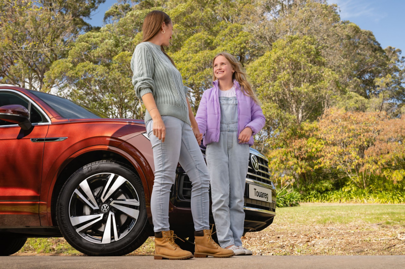 Mother and daughter next to VW Touareg in country with alloy wheels