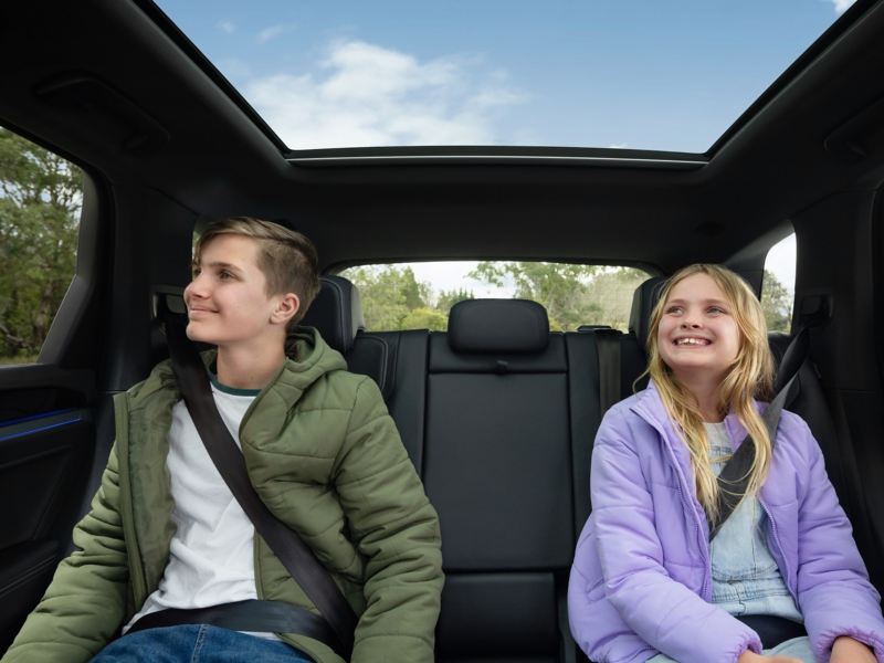 Two kids sitting on the back seat of a Volkswagen Touareg