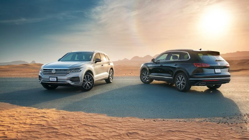 2 Volkswagen Touareg models parked next to each other on a desert road in the Middle East