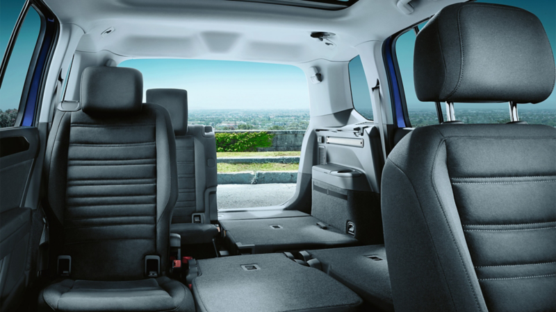 VW Touran from inside, view of front passenger seat back towards the open boot lid with some seats folded down.