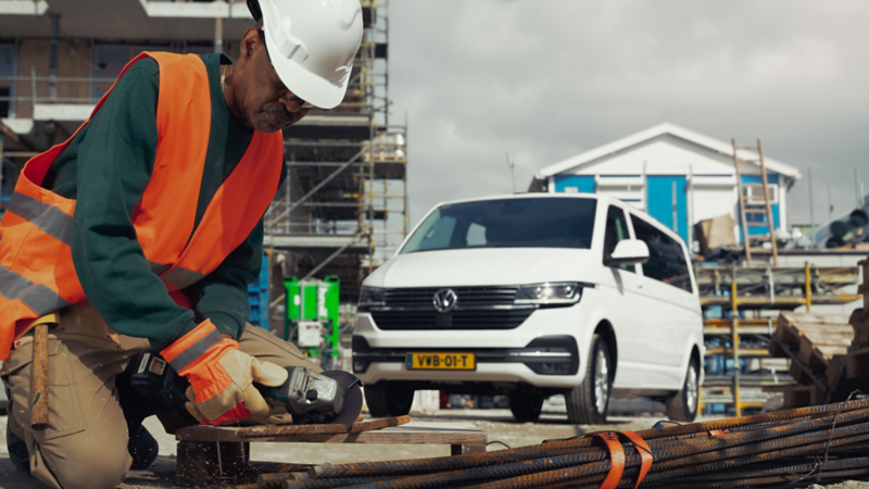 Bouwvakker die zaagt met een Transporter 6.1 op de achtergrond