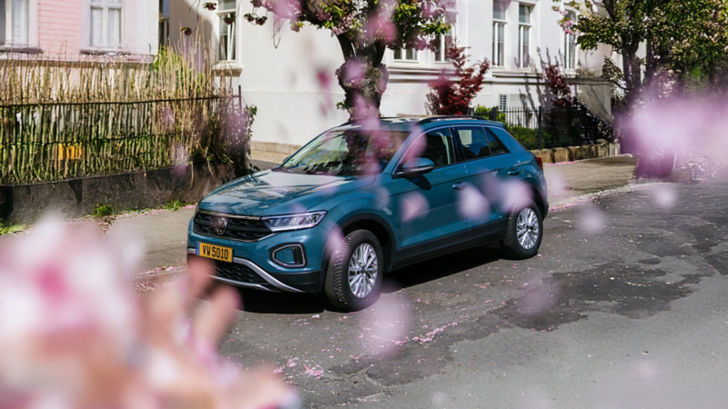 Un T-Roc bleu est garé, tandis que des pétales de cerisier tombent.