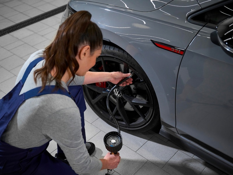 VW service employee measures tyre pressure of a VW tyre