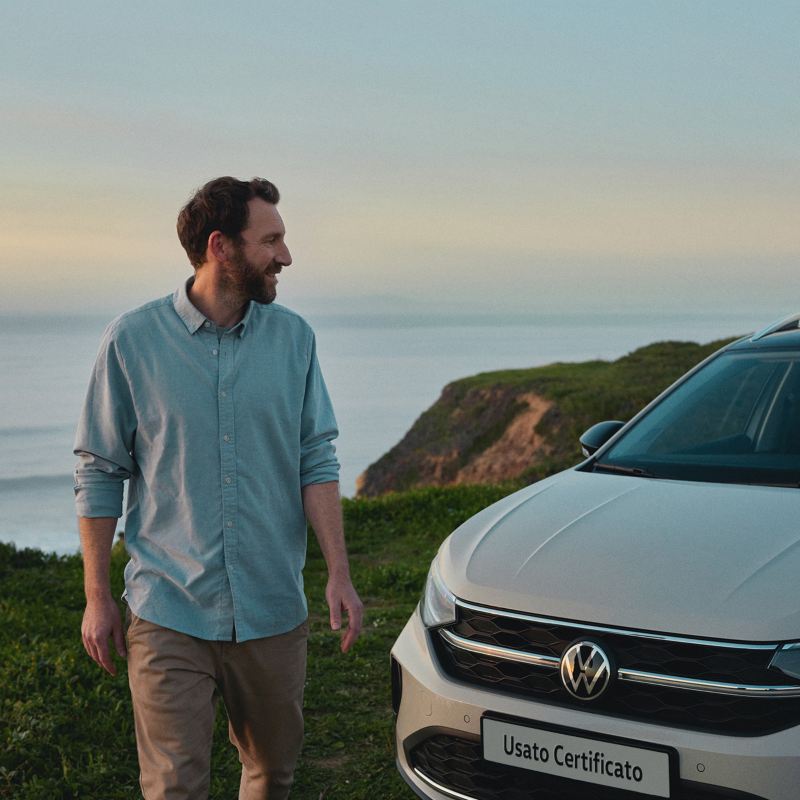 Un uomo accanto a VW Taigo con sfondo sul mare