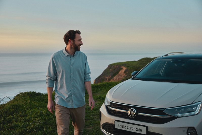 Un uomo accanto a VW Taigo con sfondo sul mare