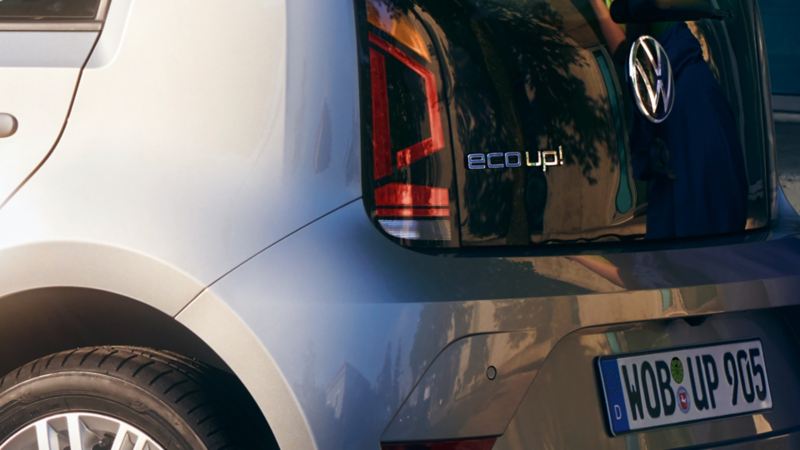 Blick auf Heckklappe eines silbernen VW eco up!, Fokus auf „eco up“ Schriftzug.