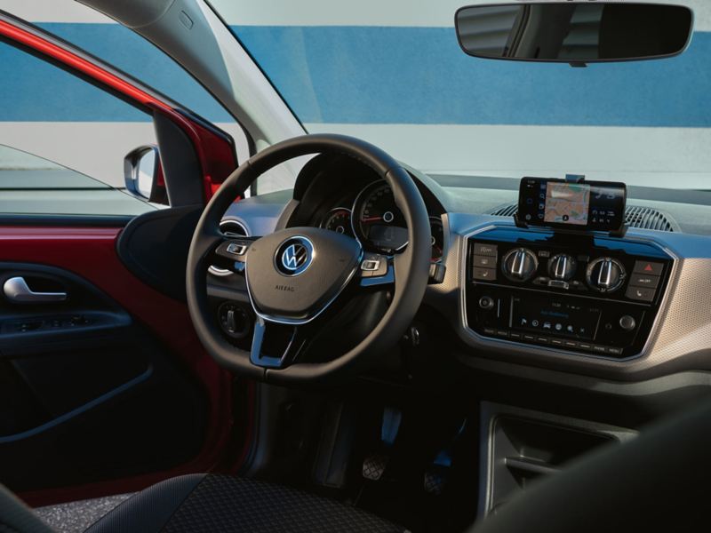 Roter VW up! ACTIVE von innen. Blick auf Multifunktionslenkrad in Leder und Cockpit mit Armatur. Tür geöffnet.