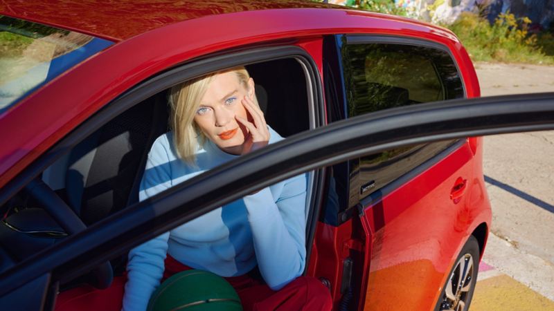 Roter VW up! ACTIVE mit geöffneter Tür seitlich aus der Nähe. Frau mit blauem Pullover auf dem Fahrersitz.