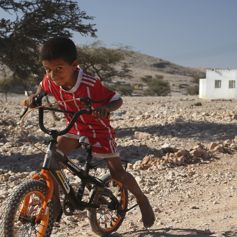 Liten kille på cykel i öknen