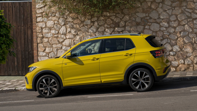 A yellow T-Cross, side view on a road
