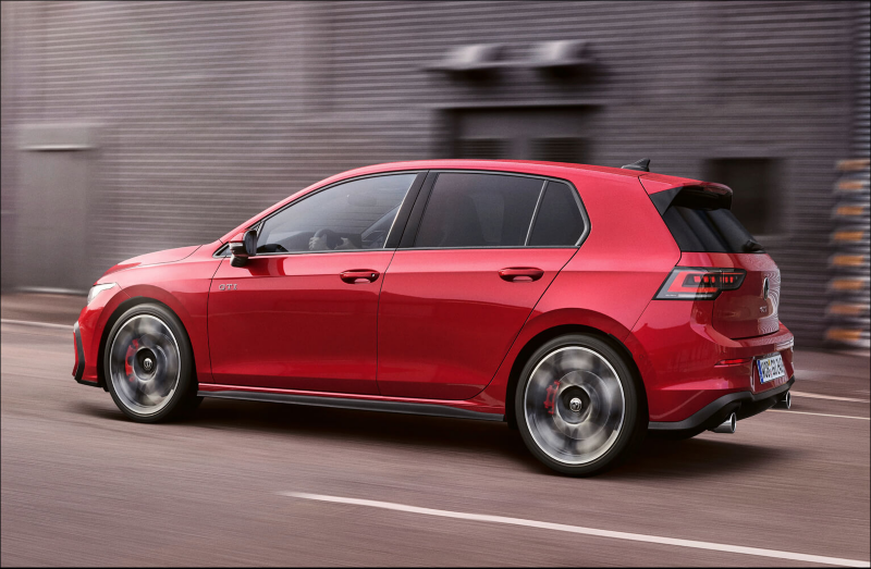 Red Volkswagen hatchback driving on a city street
