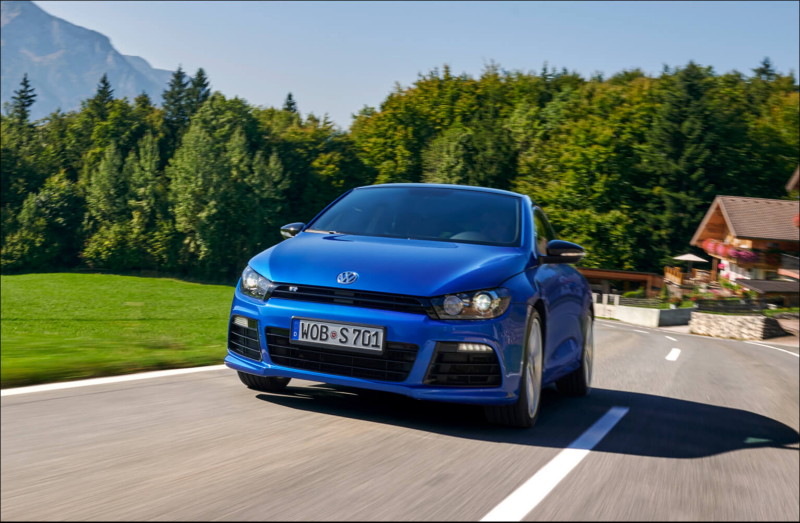 Blue Volkswagen coupé driving on a country road.