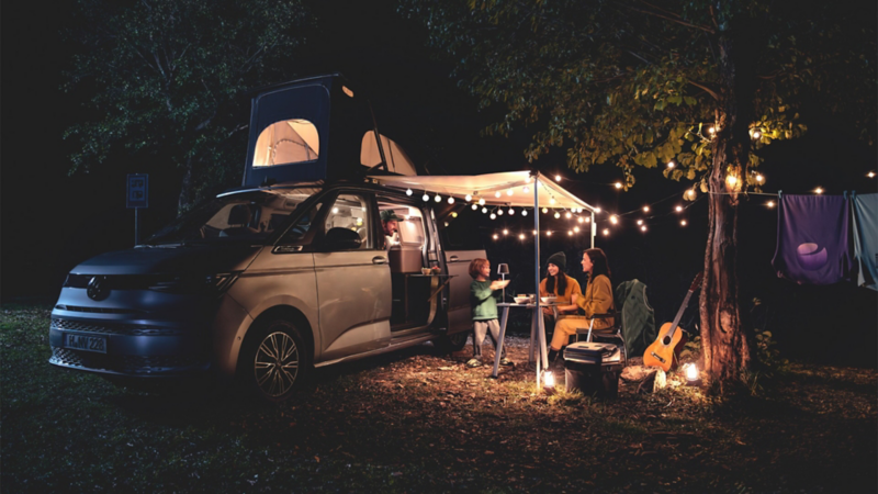 A cozy glamping situation in the evening with fairy lights in the VW California.