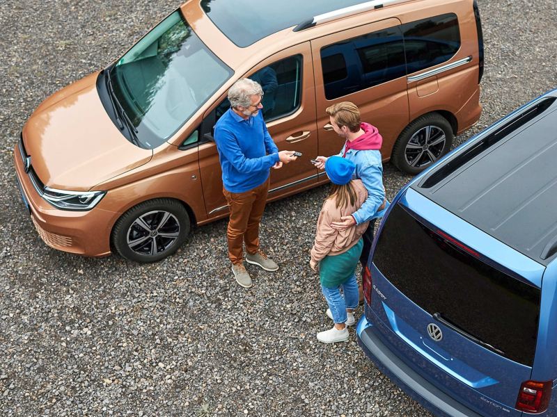 Drei Menschen stehen zwischen zwei VW Caddys.