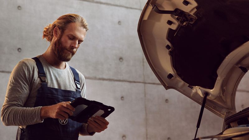 Un addetto VW consulta un tablet, di fronte a un veicolo commerciale Volkswagen.